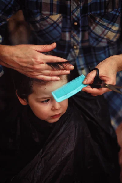 Mały chłopiec jest przycięty w salonie fryzjerskim — Zdjęcie stockowe