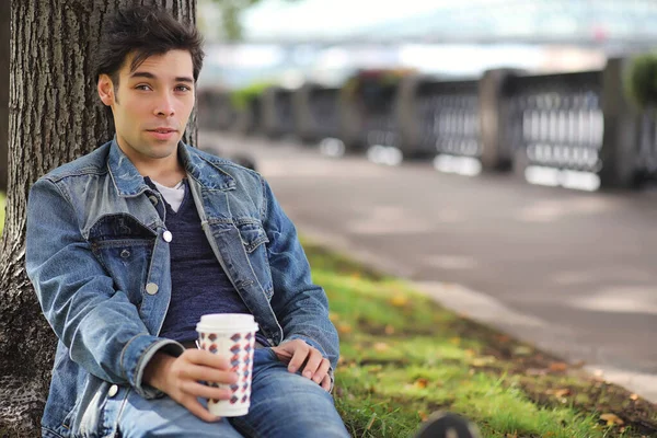 A young man walks in the park at lunch time. A man is on a walk