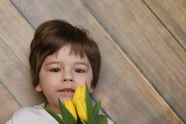 A small child with a bouquet of yellow tulips. A boy with a gift — Stock Photo, Image