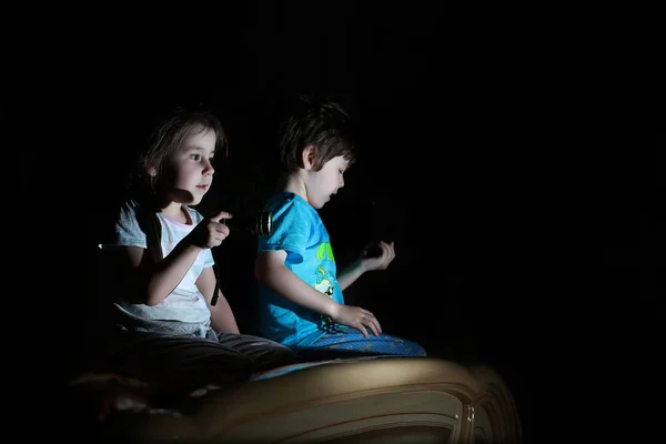 Niños pequeños en una habitación oscura viendo la televisión — Foto de Stock
