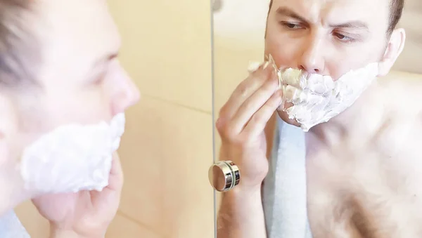 Um homem faz a barba na casa de banho pela manhã — Fotografia de Stock