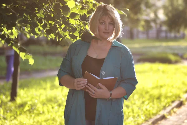 Žena starší v parku s knihou — Stock fotografie