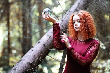 Kızıl saçlı cadı bir ritüel bir kristal top ile tutar