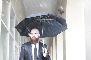 Takım elbiseli kel sakallı bir adam.