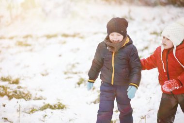 Kış parkında oynayan kalın elbiseli şirin çocuklar. 