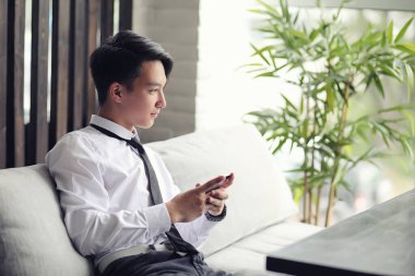 Genç Asyalı işadamı bir kafede bir ortak için bekliyor. Bu