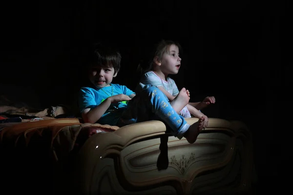 Small children in a dark room watching TV