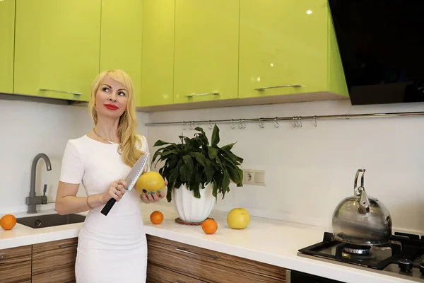 Blond flicka poserar på kameran stående i köket — Stockfoto