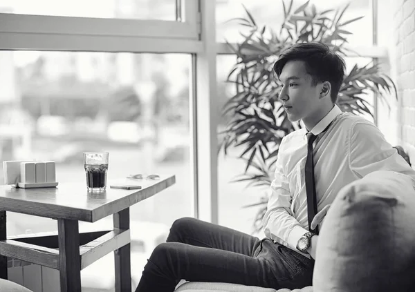 Um jovem empresário asiático está esperando por um parceiro em um café. Bu... — Fotografia de Stock