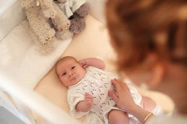 Neonato bambino carino si trova nella culla e guardando la madre — Foto Stock