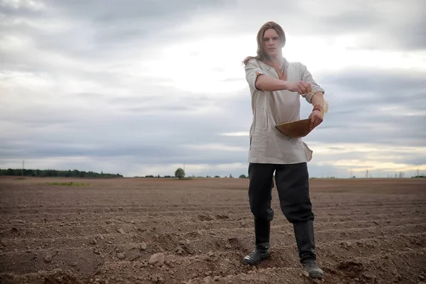 A young peasant sows the field with grain — Stock Photo, Image