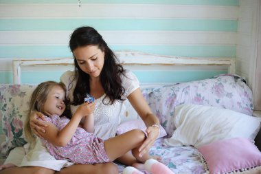 Genç kız kitap okuyor. Kızı olan genç kız yatakta oturuyor. Bahçenin yanındaki köyde yazlık ev. Köyde genç bir anne ve kız var..