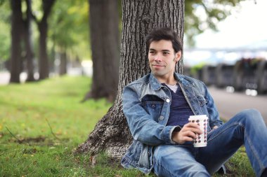 Genç bir adam öğle yemeği zamanında parkta yürür. Bir adam yürüyüşe çıktı. 