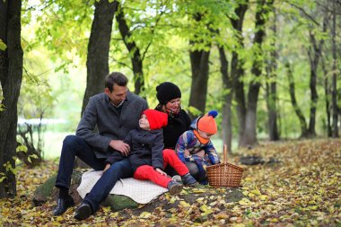 Çocuklu genç bir aile baharda parkta yürüyüşe çıkıyor.