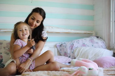 Genç kız kitap okuyor. Kızı olan genç kız yatakta oturuyor. Bahçenin yanındaki köyde yazlık ev. Köyde genç bir anne ve kız var..