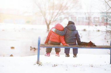 Kış parkında oynayan kalın elbiseli şirin çocuklar. 