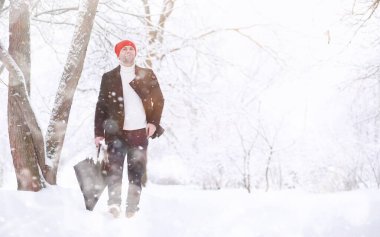 Parkta yürüyen bir adam. Genç adam kışın karla kaplı