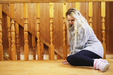 Genç bir kız kazakla merdivende oturuyor.