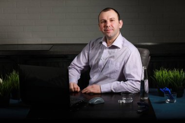 Masada oturan ve dizüstü bilgisayarda çalışan adam