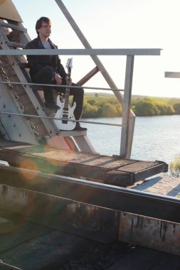 Adam açık havada ve endüstriyel yatay olarak bir elektro gitar ile