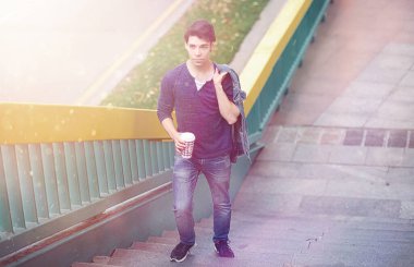 Genç bir adam öğle yemeği zamanında parkta yürür. Bir adam yürüyüşe çıktı. 