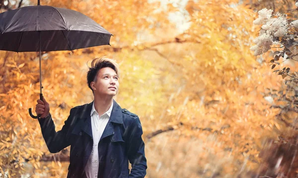 Autunno tempo piovoso e un giovane uomo con un ombrello — Foto Stock