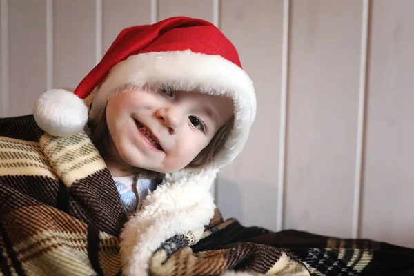 Uma Criança Pequena Chapéu Papai Noel Senta Uma Cadeira — Fotografia de Stock