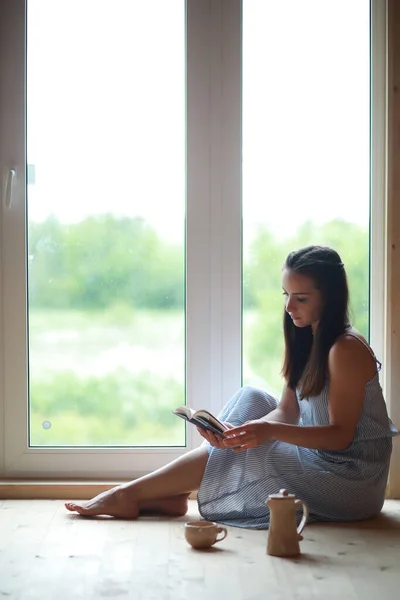 En flicka på fönstret i huset — Stockfoto