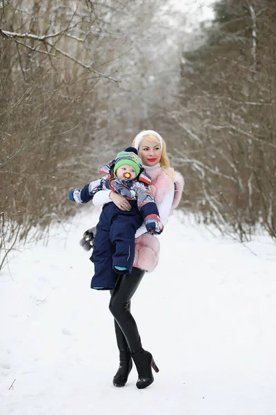 Ung mamma går på en vinterdag med en baby i famnen i th — Stockfoto