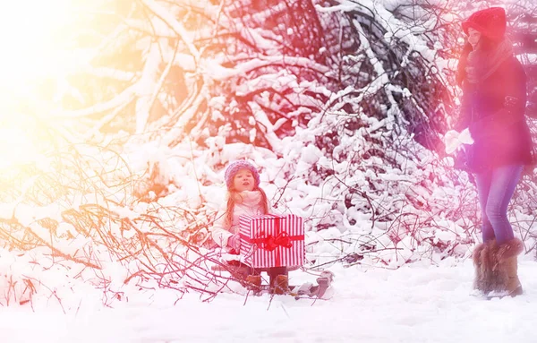 A winter fairy tale, a young mother and her daughter ride a sled — Stock Photo, Image