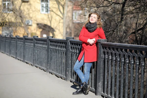 Chica bonita en un paseo en abrigo rojo en la ciudad — Foto de Stock