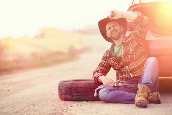 Man sitter på vägen av bilen — Stockfoto