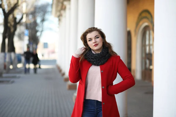 Chica bonita en un paseo en abrigo rojo en la ciudad — Foto de Stock