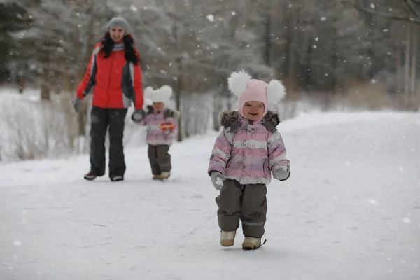 Los niños caminan en el parque en invierno. Bosque de invierno una familia con — Foto de Stock