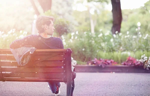 A young man walks in the park at lunch time. A man is on a walk