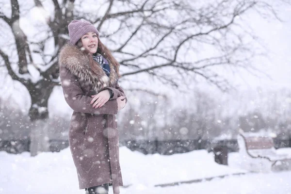 Fata într-un parc de iarnă în căderea zăpezii — Fotografie, imagine de stoc