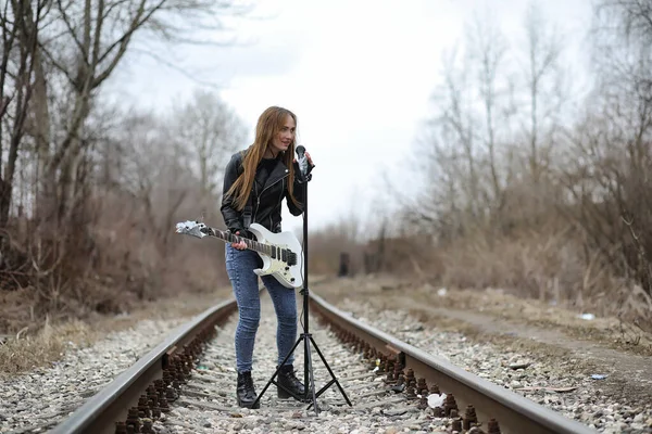 En rock musiker flicka i en läderjacka med en gitarr — Stockfoto