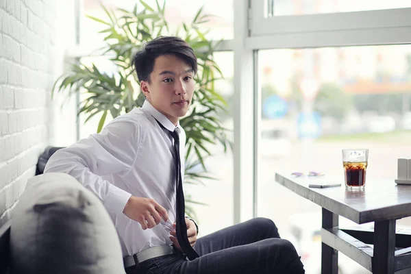 Um jovem empresário asiático está esperando por um parceiro em um café. Bu... — Fotografia de Stock