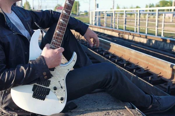 Homem com uma guitarra elétrica na paisagem industrial ao ar livre — Fotografia de Stock