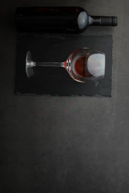 Şarap kadehi ve siyah şarap şişesi. Ceviz peyniri ve domates.