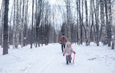 Çocuk kış parkında oynuyor ve ailesiyle eğleniyor.
