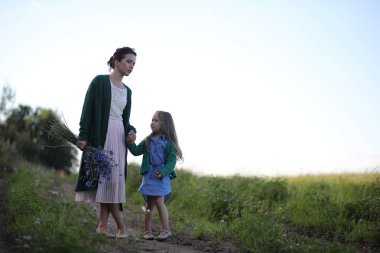 Anne ve kızı yolda yürüyor.