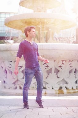 Genç bir adam öğle yemeği zamanında parkta yürür. Bir adam yürüyüşe çıktı. 