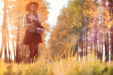 Parkta bir yürüyüş üzerinde şapkalı bir kız. Bir kızla bir sepet yürüyüş