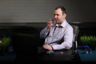 Masada oturan ve dizüstü bilgisayarda çalışan adam