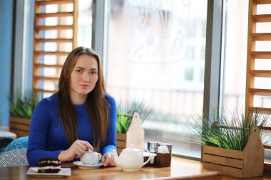 Genç kız kafede oturur ve çay içer