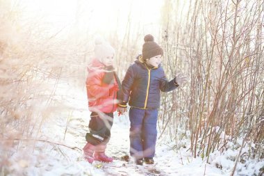 Kış parkında oynayan kalın elbiseli şirin çocuklar. 