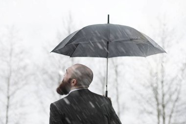 Takım elbiseli kel sakallı bir adam.
