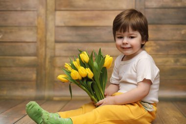 Bir buket Sarı laleler ile küçük bir çocuk. Bir çocuk bir hediye ile