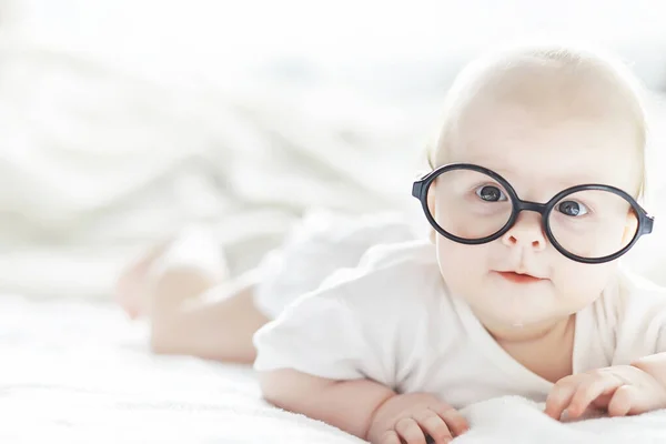 一个新生婴儿戴着眼镜躺在柔软的床上. — 图库照片